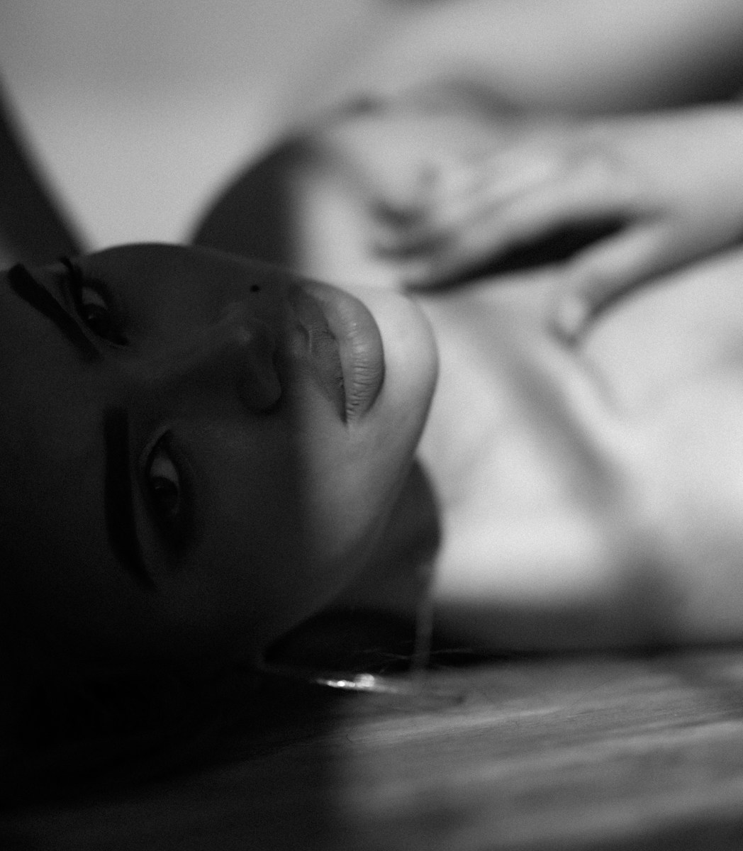 a black and white photo of a woman laying on the floor