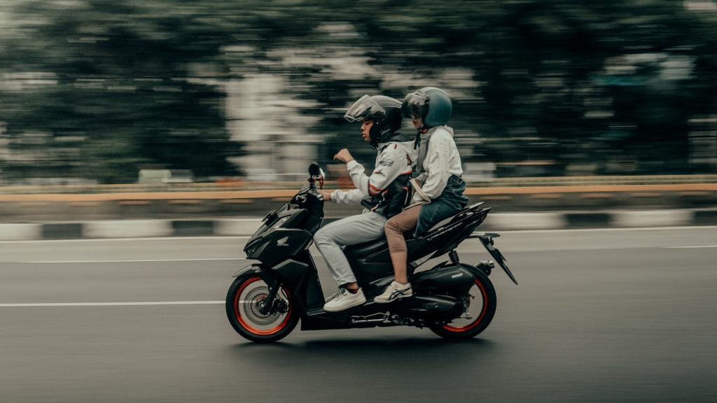 Two people riding a motorcycle on a city street